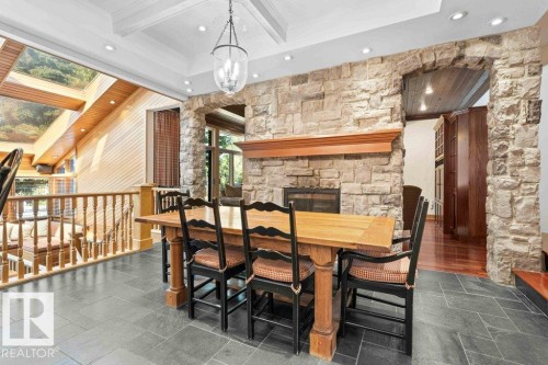 Dining area featuring two sided wood burning fireplace, coffered ceiling and slate flooring. - 738 Wheeler Road, Edmonton, AB 