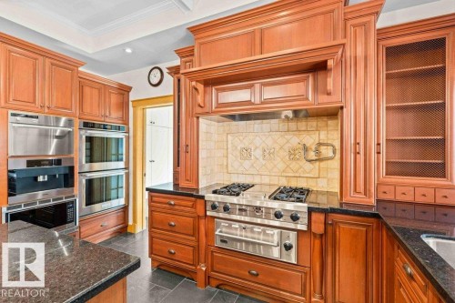 Kitchen with granite countertops, custom tile backsplash, Miele, Subzero and KitchenAid appliances featuring trash compactor, dual wall ovens plus garburator. - 738 Wheeler Road, Edmonton, AB 