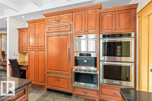 Kitchen with granite countertops, custom tile backsplash, Miele, Subzero and KitchenAid appliances featuring trash compactor, dual wall ovens plus garburator. - 738 Wheeler Road, Edmonton, AB 