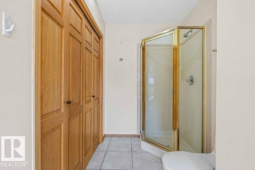 Full bathroom featuring light tile patterned flooring, a stall shower, and a closet - 738 Wheeler Road, Edmonton, AB 