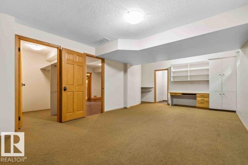 Unfurnished bedroom with a walk in closet, light colored carpet, a textured ceiling, and built in study area - 738 Wheeler Road, Edmonton, AB 