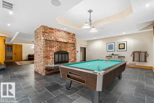 Rec room with two sided wood burning fireplace, heated slate flooring and flush mounted ceiling speakers. - 738 Wheeler Road, Edmonton, AB 