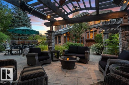 Patio terrace at dusk featuring the pergola, radiant heaters, dining area and pool - 738 Wheeler Road, Edmonton, AB 