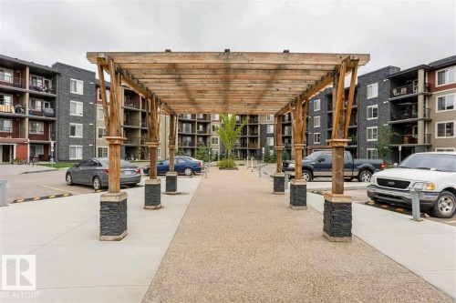 Wood pergola structure over a textured concrete walkway - 328 3315 James Mowatt Trail, Edmonton, AB 