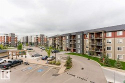 Apartment complex exterior featuring multiple buildings with balconies, paved parking areas, a landscaped driveway, and a wood pergola - 