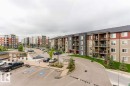 Apartment complex exterior featuring multiple buildings with balconies, paved parking areas, a landscaped driveway, and a wood pergola - 328 3315 James Mowatt Trail, Edmonton, AB 