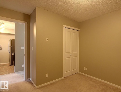 Neutral-toned room with plush carpet flooring, a bifold closet, and white trim - 328 3315 James Mowatt Trail, Edmonton, AB 