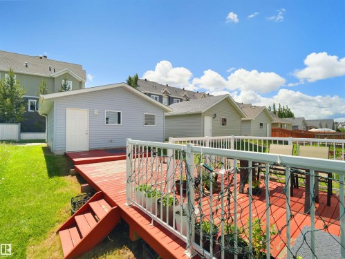 Expansive red-stained wood deck featuring white railings, providing ample outdoor living space - 7827 22 Avenue, Edmonton, AB 