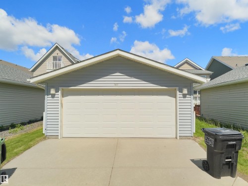 Attached two-car garage with a white overhead door and light gray horizontal siding - 7827 22 Avenue, Edmonton, AB 
