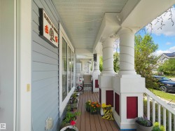 Covered porch featuring light blue siding, white trim, wood-finish flooring, and multiple white columns with red bases - 