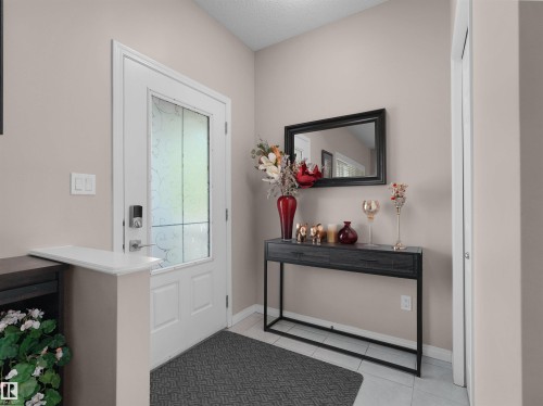 Entryway featuring a white door with frosted glass, smart lock hardware, and light-toned wall finishes - 7827 22 Avenue, Edmonton, AB 