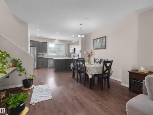 Open-concept living space featuring wood-finish flooring, a kitchen with stainless steel appliances, dark wood cabinetry, and a central island - 7827 22 Avenue, Edmonton, AB 
