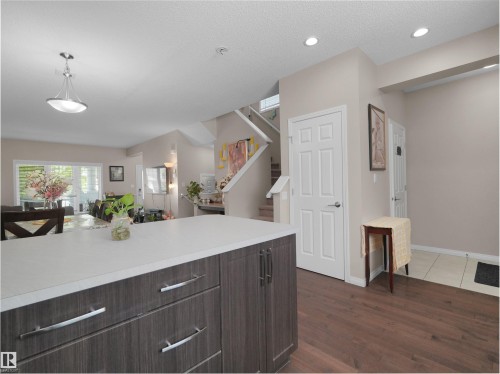 Kitchen island with a light-toned countertop, wood-finish cabinetry, and stainless steel hardware - 7827 22 Avenue, Edmonton, AB 