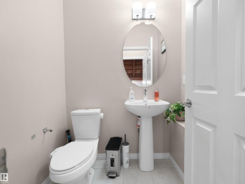 Pedestal sink with an oval mirror and two-light vanity fixture - 7827 22 Avenue, Edmonton, AB 