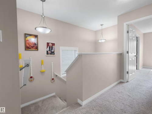 Upper-level landing featuring neutral-toned walls, light carpet flooring, and a white paneled door - 7827 22 Avenue, Edmonton, AB 