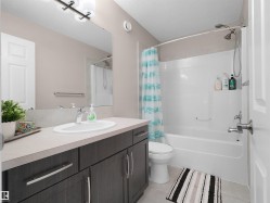 Bathroom featuring a dark wood-finish vanity with a light countertop, an undermount sink, and chrome fixtures - 