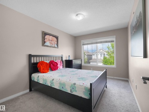 Spacious room featuring neutral paint, light gray carpeting, a large window with blinds, and white trim - 7827 22 Avenue, Edmonton, AB 