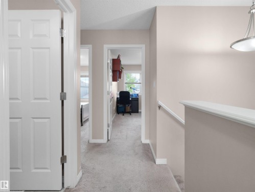 Carpeted hallway with neutral wall paint and white trim - 7827 22 Avenue, Edmonton, AB 