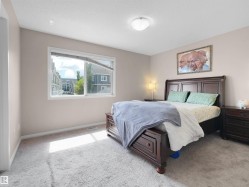 Carpeted bedroom featuring a large window, neutral wall paint, and a flush-mount ceiling light fixture - 