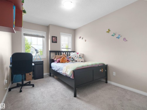 Carpeted interior room featuring two windows with natural light, neutral wall tones, and white trim - 7827 22 Avenue, Edmonton, AB 