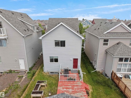 Two-story property featuring light gray horizontal siding and a contrasting red entry door - 7827 22 Avenue, Edmonton, AB 