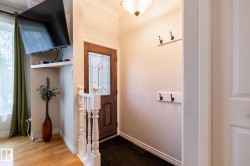 Entryway featuring a wood-panel door with decorative glass, an overhead light fixture, and crown molding - 