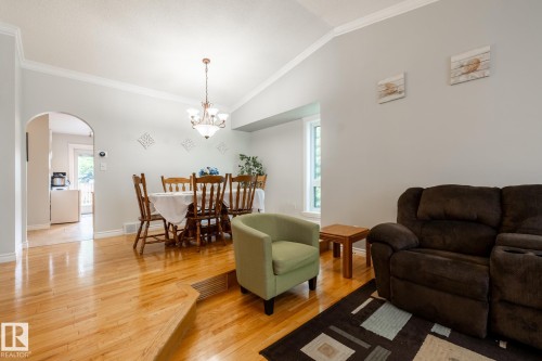 Spacious interior featuring wood-finish flooring, vaulted ceilings, and an arched doorway - 27 Danforth Crescent, St. Albert, AB 