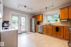 Kitchen featuring natural wood-finish cabinetry, stainless steel appliances, and a light-toned tile backsplash - 