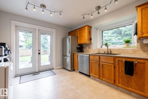 Kitchen featuring wood cabinetry, stainless steel appliances, a tile backsplash, and track lighting - 27 Danforth Crescent, St. Albert, AB 