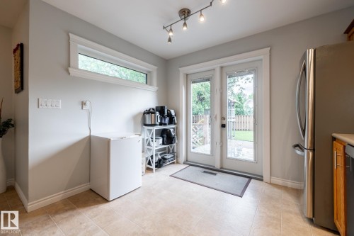 Kitchen area featuring patio doors, a transom window, ceramic tile flooring, a stainless steel refrigerator, and track lighting - 27 Danforth Crescent, St. Albert, AB 