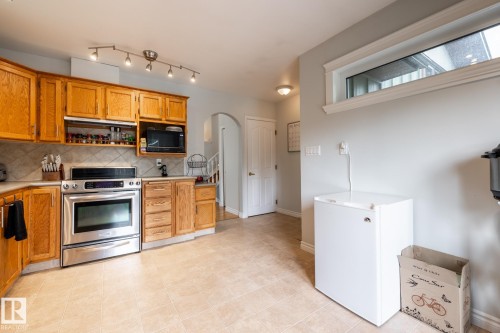 Kitchen with wood cabinetry, stainless steel oven, and tile backsplash - 27 Danforth Crescent, St. Albert, AB 