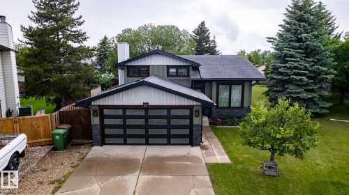 Contemporary split-level residence featuring a modern garage door with frosted glass panels, a stone veneer facade, and a pitched asphalt shingle roof - 27 Danforth Crescent, St. Albert, AB 