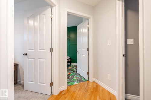 Hallway featuring light-toned walls, wood-finish flooring, and white trim - 27 Danforth Crescent, St. Albert, AB 