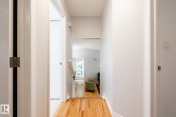 Hallway with wood-finish flooring, light-toned walls, and white trim - 