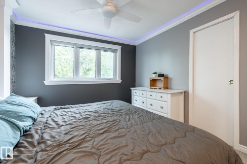 Bedroom featuring a triple window with white trim, ceiling fan, crown molding with accent lighting, and a solid core door - 27 Danforth Crescent, St. Albert, AB 