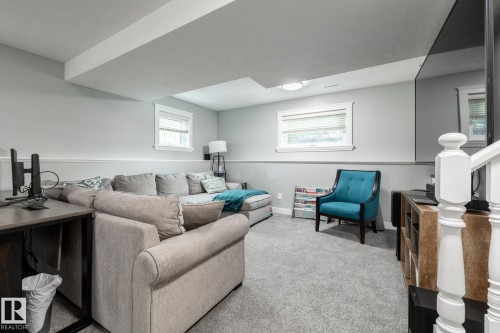 Carpeted recreation room featuring white trim, two windows, recessed lighting, and a built-in media console - 27 Danforth Crescent, St. Albert, AB 