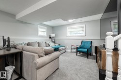 Carpeted recreation room featuring white trim, two windows, recessed lighting, and a built-in media console - 