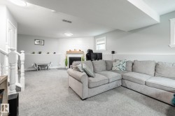 Spacious lower-level area featuring a fireplace with a wood-finish mantel and shiplap-style surround - 