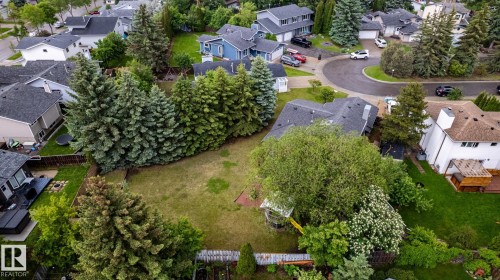 Expansive grassy backyard featuring a fenced perimeter and mature trees - 27 Danforth Crescent, St. Albert, AB 