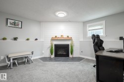 Carpeted room featuring a fireplace with a wood mantle and shiplap surround, a single window, and a built-in shelf with trim - 