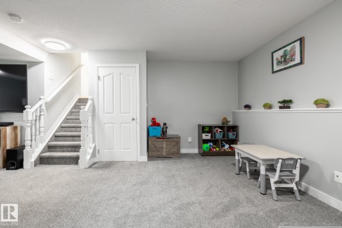 Spacious room featuring light gray walls, light gray carpet, and a white paneled door - 27 Danforth Crescent, St. Albert, AB 