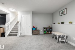 Spacious room featuring light gray walls, light gray carpet, and a white paneled door - 