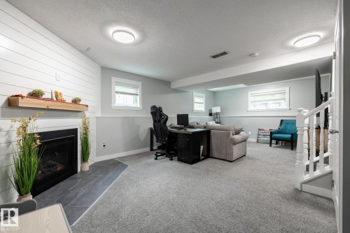 Finished lower level featuring a fireplace with shiplap surround, wood mantel, and tile hearth - 27 Danforth Crescent, St. Albert, AB 