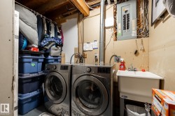 Dedicated utility area featuring a wall-mounted electrical panel, exposed ceiling joists, and a utility sink - 