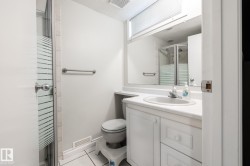 Bathroom featuring a glass-enclosed shower, white vanity with integrated sink, white tile flooring, and mirrored medicine cabinet - 