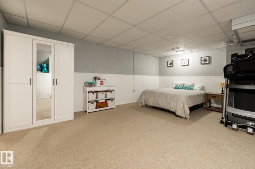 Spacious room featuring neutral carpet flooring, a white paneled wainscoting, and a drop ceiling with integrated lighting - 27 Danforth Crescent, St. Albert, AB 