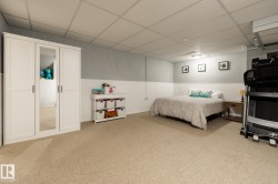 Spacious room featuring neutral carpet flooring, a white paneled wainscoting, and a drop ceiling with integrated lighting - 