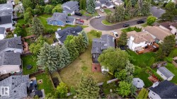 Expansive property featuring a large backyard with mature trees, a manicured lawn, and a wooden fence - 