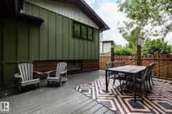 Expansive outdoor deck featuring wood-finish flooring, a decorative area rug, and a perimeter privacy fence - 