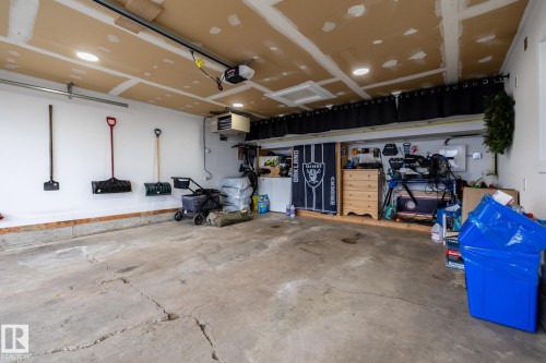 Spacious garage featuring a concrete floor, white painted walls, and an unfinished ceiling - 27 Danforth Crescent, St. Albert, AB 
